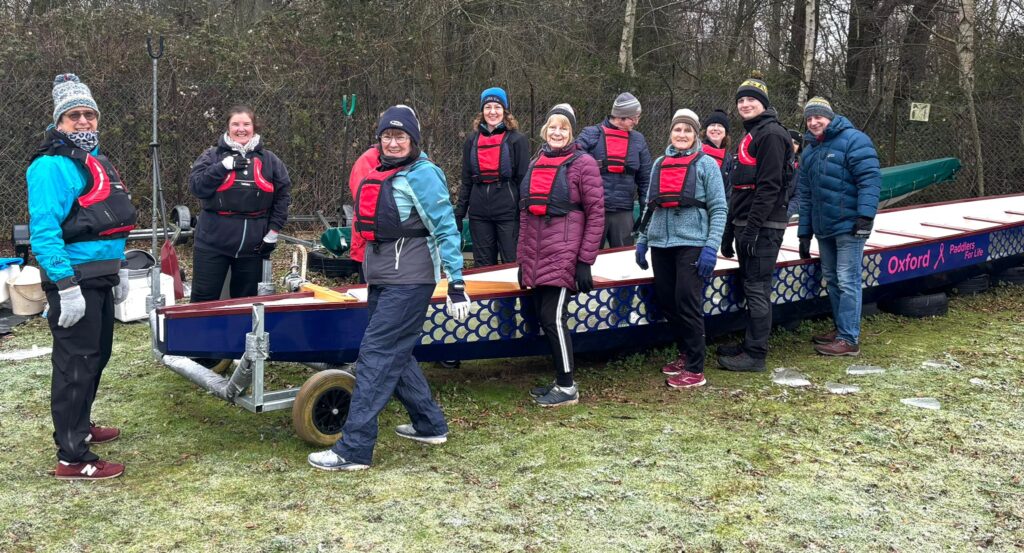 Group of paddlers standing on either side of the dragonboat.